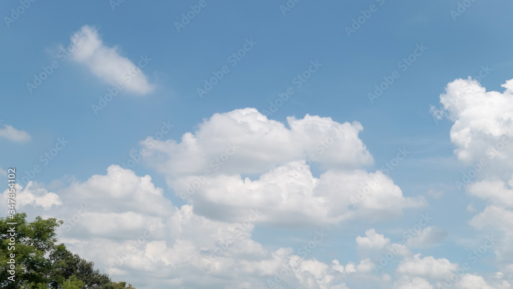 Blue sky with white soft clouds. Simple outdoor sky background. Blue sky with white soft clouds. Simple outdoor sky background.