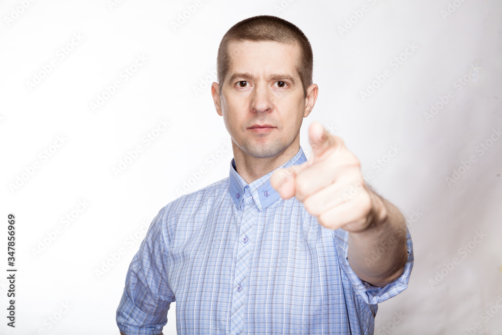 portrait of a pretty successful man in a classic blue shirt; Shows his index finger forward. look into the camera. Isolated portrait of a pretty successful man in a classic blue shirt; Shows his index finger forward. look into the camera. Isolated