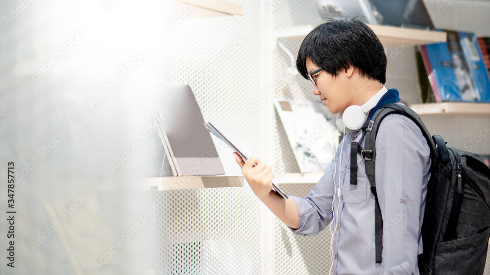 Young Asian man wearing glasses and headphones choosing vinyl record in music record shop. Music addict or Melomaniac concept Young Asian man wearing glasses and headphones choosing vinyl record in music record shop. Music addict or Melomaniac concept