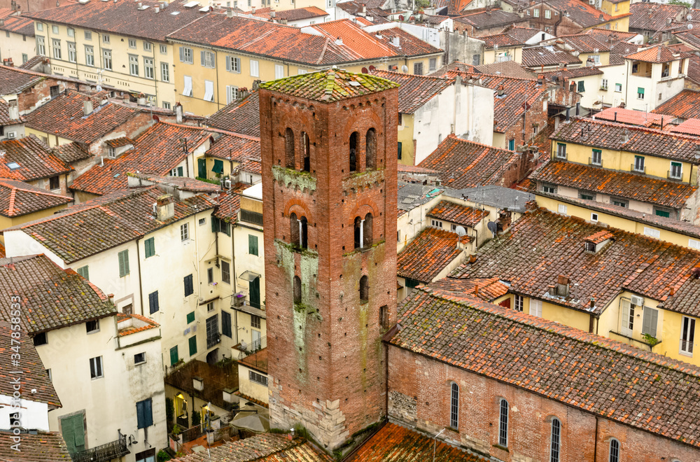 From the Guinigi's tower a landscape aerial view of the typical italian red roofs of the medieval town of Lucca in Tuscany, Italy during a rainy winter day 