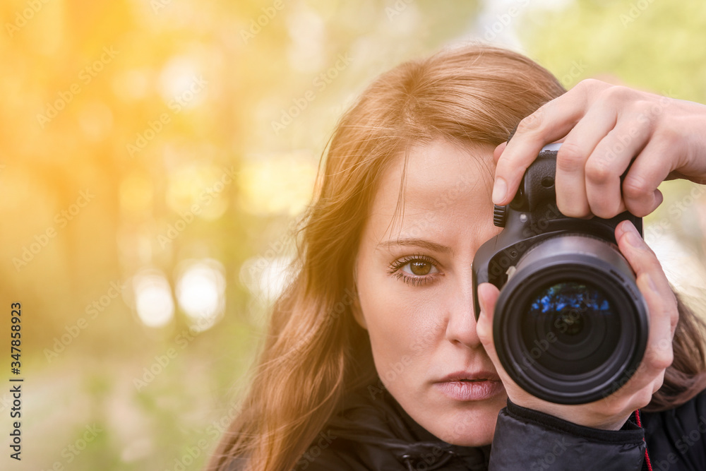 photographer girl, close-up portrait. The girl model takes photos, looking at the viewer and into the lens of the outdoor camera. red hair develop, copyspace photographer girl, close-up portrait. The girl model takes photos, looking at the viewer and into the lens of the outdoor camera. red hair develop, copyspace
