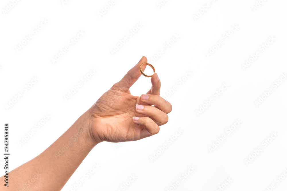Hand of caucasian young man holding marriage ring over isolated white background Hand of caucasian young man holding marriage ring over isolated white background