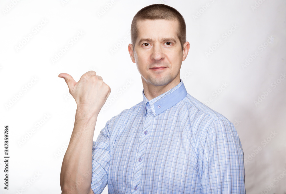 portrait of a pretty successful man in a classic blue shirt; Shows his thumb to the side; look into the camera. Isolated