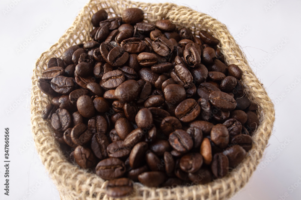 Roasted coffee beans in jute bag on white background Roasted coffee beans in jute bag on white background