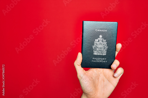 Beautiful hand of man holding canada canadian passport identification over isolated red background