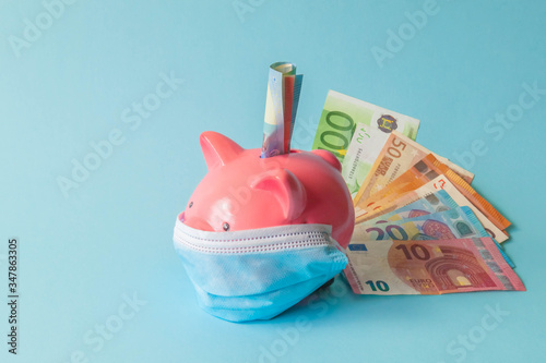 Piggy bank with protective face mask and euro notes on isolated background