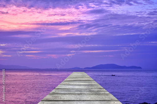Fototapeta Naklejka Na Ścianę i Meble -  Sunset at sea and old wooden bridgeมPerspective view of wooden pier on the sea at sunset with perfectly specular reflection,wooden retro deck and sunrise or sunset sky/ Summer holidays background.