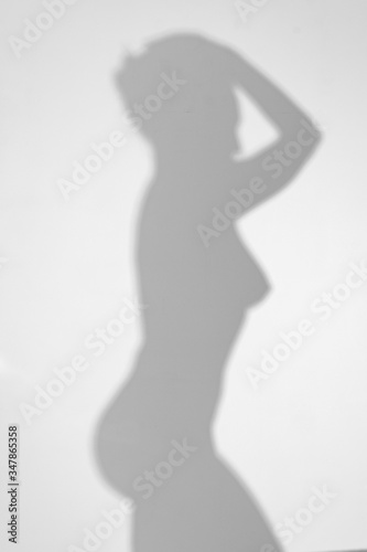 a shadow on the white wall from a naked woman. You can see the outline of the chest and buttocks.