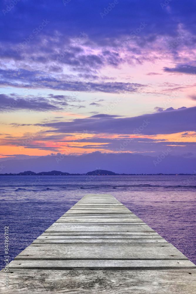 Sunset at sea and old wooden bridgeมPerspective view of wooden pier on the sea at sunset with perfectly specular reflection,wooden retro deck and sunrise or sunset sky/ Summer holidays background.