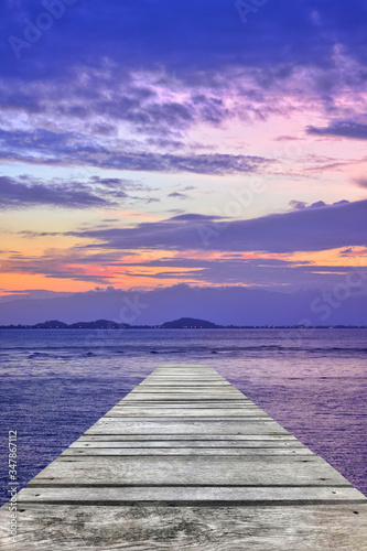 Sunset at sea and old wooden bridge   Perspective view of wooden pier on the sea at sunset with perfectly specular reflection wooden retro deck and sunrise or sunset sky  Summer holidays background.