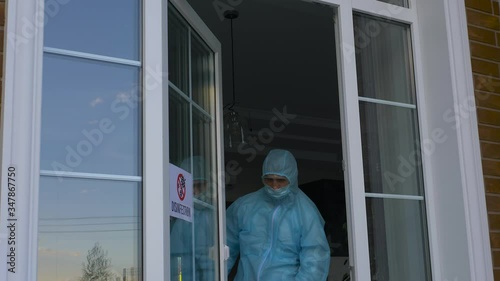 Coronavirus Pandemic. A disinfector in a protective suit and mask sprays disinfectants in house or office. Protection agsinst COVID-19 disease. Prevention of spreding pneumonia virus with surfaces. photo