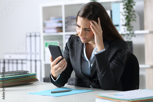 Sad executive reading bad news on phone at office