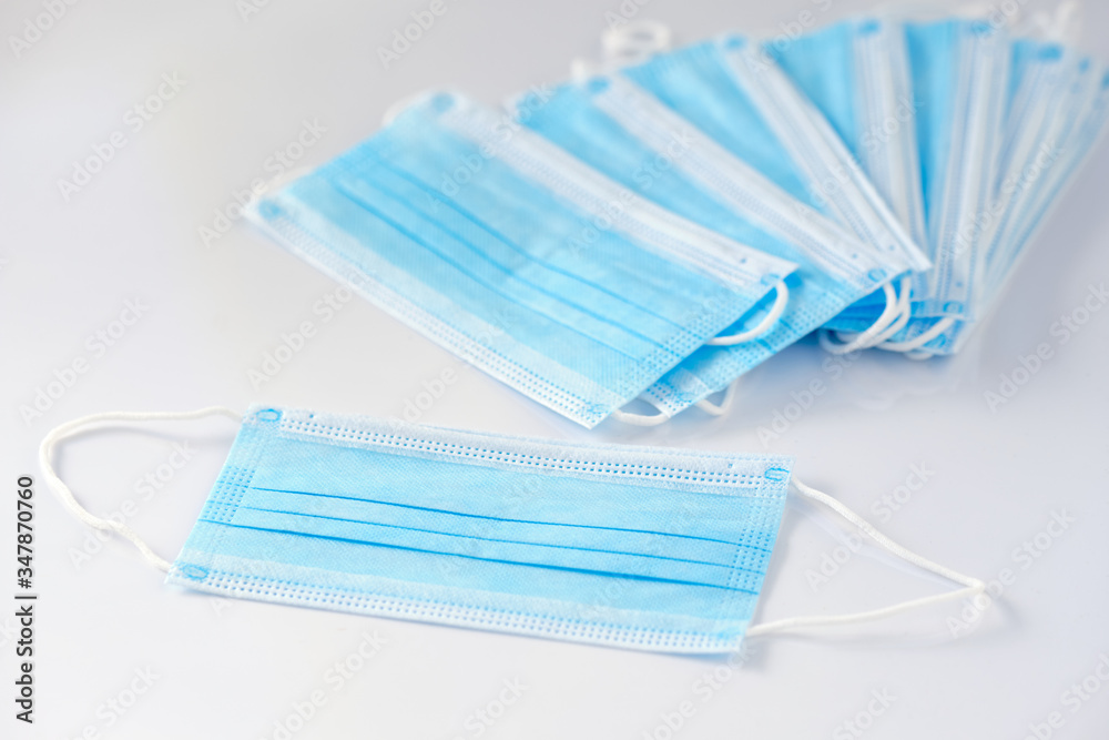 A stack of new unused disposable face masks lying on white background. Seen in Germany in May during corona crisis. A stack of new unused disposable face masks lying on white background. Seen in Germany in May during corona crisis.