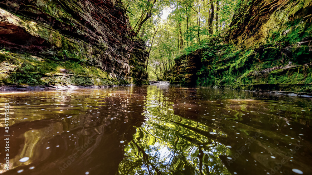 A hidden ravine with a small shallow stream flowing between rock walls in Devil's Lake State Park near Baraboo, Wisconsin, USA. A hidden ravine with a small shallow stream flowing between rock walls in Devil's Lake State Park near Baraboo, Wisconsin, USA.