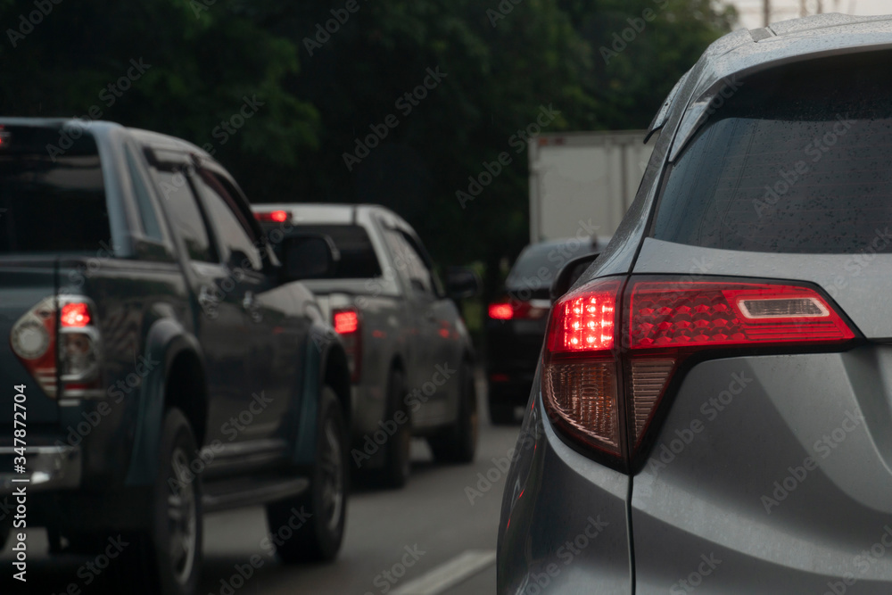Rear side of gray car with open brake light on the road and other cars stop by traffic jam.