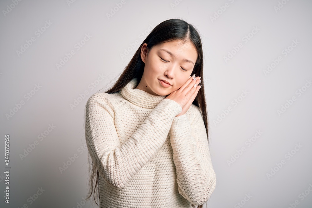 Young beautiful asian woman wearing casual sweater standing over isolated background sleeping tired dreaming and posing with hands together while smiling with closed eyes.