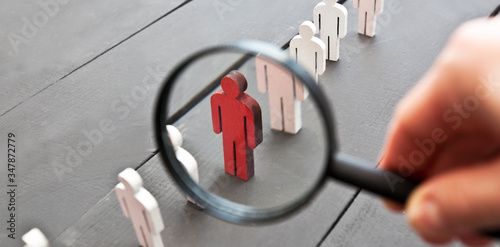 The view through the magnifier on the one wooden red person between other people photo