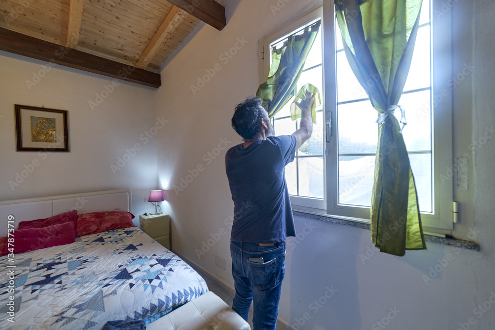 man cleaning the windows of his bedroom during covid19 quarantine