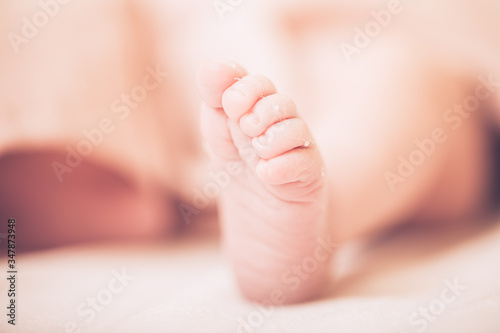 Cute newborn baby legs on a light blanket. Sleeping baby on a light background. Closeup newborn legs. Baby goods packing template. Medical and healthy concept.