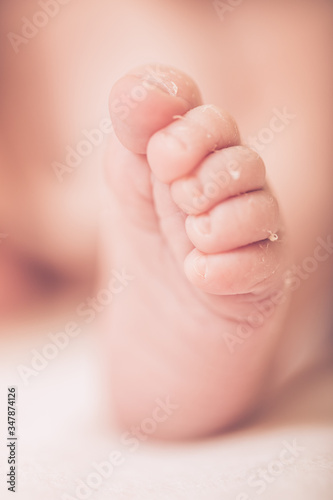 Cute newborn baby legs on a light blanket. Sleeping baby on a light background. Closeup newborn legs. Baby goods packing template. Medical and healthy concept.