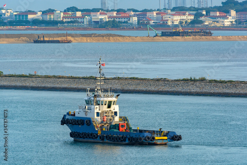 Canvas Print Tugboat passes underway along the the land reclamation development site shoreline