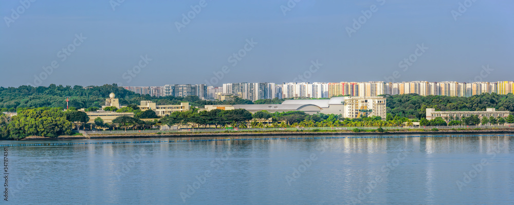 Fototapeta premium Panoramic sight of the Johor strait coast with Pasir Ris Coast Industrial Parks in Singapore with Punggol Town on the background.