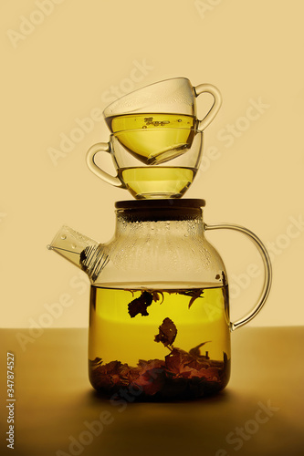 Green tea in a teapot and two cups on top, photographed in backlight