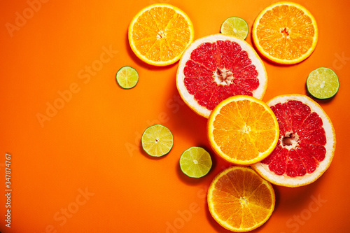 Fresh slices of citrus on the orange background. View from above. Place for text.