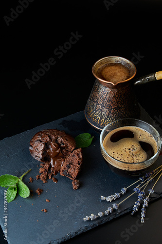 A delicious chocolate muffin, a cup of black coffee, a cezve with custard coffee. Decorated with mint and lavender.