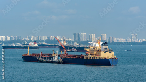 Loading anchored oil supertanker via a ship-to-ship oil transfer (STS) from raid tanker