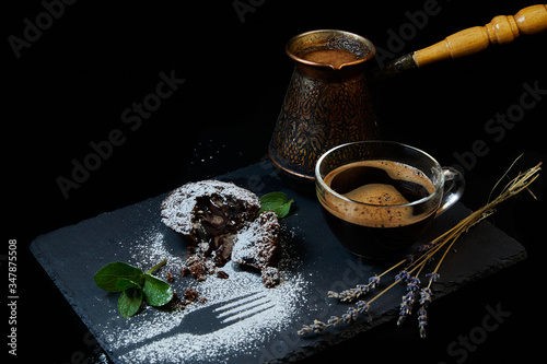 A delicious chocolate muffin, a cup of black coffee, a cezve with custard coffee. Decorated with mint and lavender.