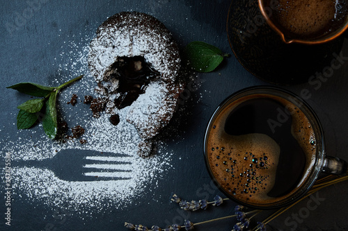 A delicious chocolate muffin, a cup of black coffee, a cezve with custard coffee. Decorated with mint and lavender.