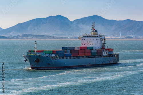Foto Container vessel passes underway along Gwangyang bay shore at sunny day