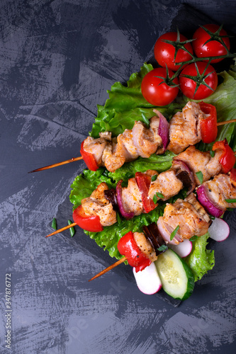 Shashlik made of chicken and vegetables on wooden skewers on the grey table