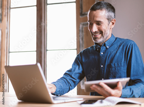 Good looking middle aged modern man is having a video meeting with colleages or family or friends, from home