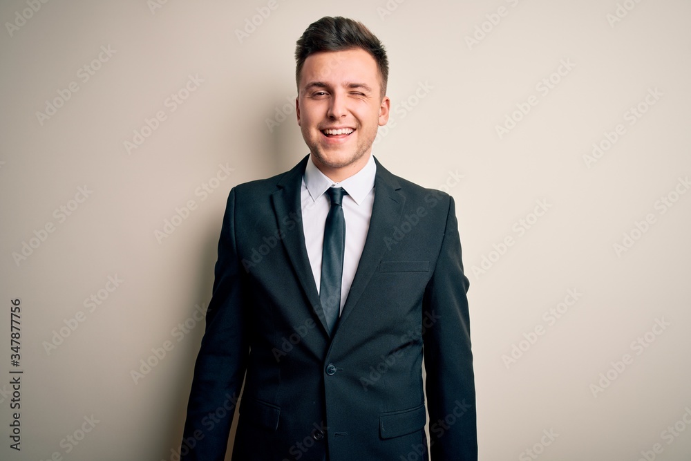 Young handsome business man wearing elegant suit and tie over isolated background winking looking at the camera with sexy expression, cheerful and happy face. Young handsome business man wearing elegant suit and tie over isolated background winking looking at the camera with sexy expression, cheerful and happy face.