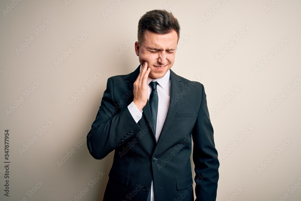 Young handsome business man wearing elegant suit and tie over isolated background touching mouth with hand with painful expression because of toothache or dental illness on teeth. Dentist Young handsome business man wearing elegant suit and tie over isolated background touching mouth with hand with painful expression because of toothache or dental illness on teeth. Dentist