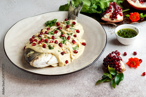 Lebanese fish with tahini sauce, pomegranate seeds and almonds  (SAMKE HARRA) photo