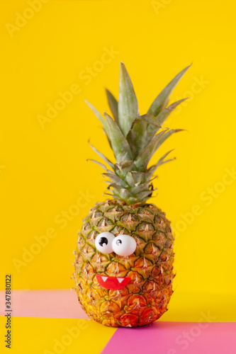 pineapple fruit with funny eyes on a yellow pink background