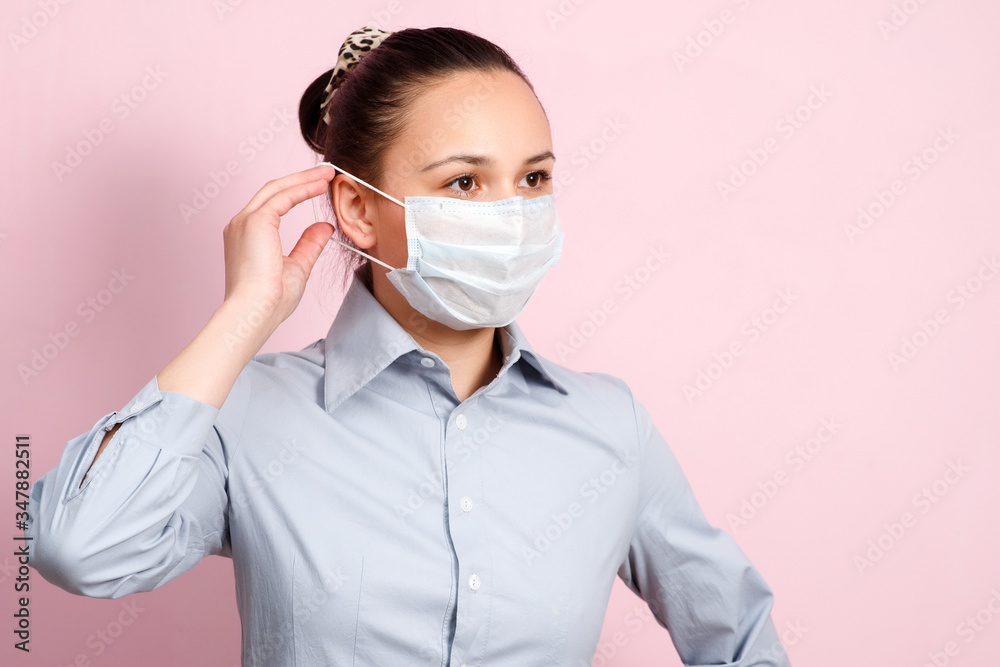 Studio portrait of young woman wearing a face mask, looking at camera, close up, isolated on pink background. Flu epidemic, dust allergy, protection against virus Studio portrait of young woman wearing a face mask, looking at camera, close up, isolated on pink background. Flu epidemic, dust allergy, protection against virus