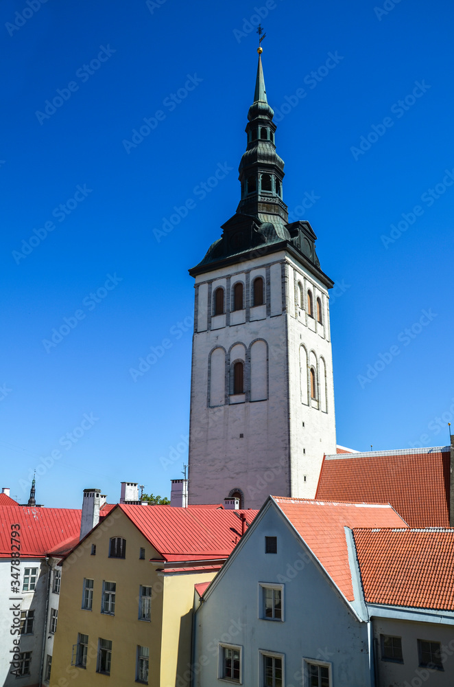 The view of bell tower of the medieval Former Lutheran Church of St. Nicholas (Niguliste Kirik), bright roofs and colorful houses in the old historical center of Tallinn, Estonia The view of bell tower of the medieval Former Lutheran Church of St. Nicholas (Niguliste Kirik), bright roofs and colorful houses in the old historical center of Tallinn, Estonia