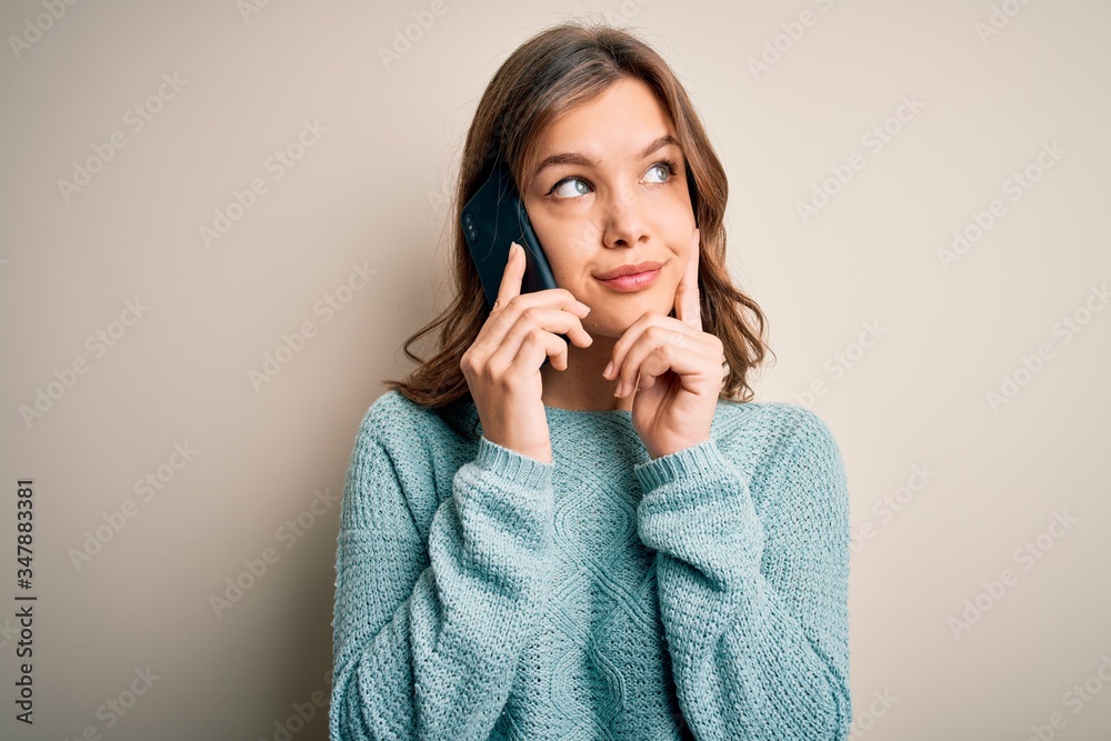 Young blonde girl having a conversation talking on smartphone over isolated background serious face thinking about question, very confused idea Young blonde girl having a conversation talking on smartphone over isolated background serious face thinking about question, very confused idea