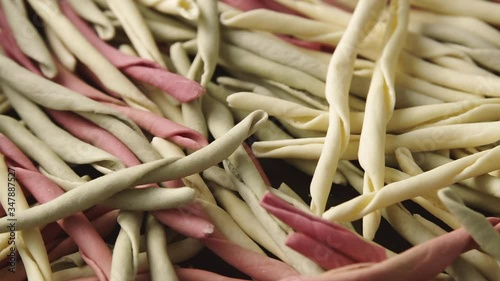 Traditional raw Italian fileja pasta of various colors slow rotation. Macro shot