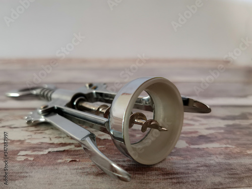 Kitchen utensils. Close-up of a metal corkscrew for wine on background with aged wooden boards. Image with selective focus and toning.