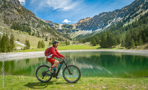 pretty senior woman riding her electric mountain bike at the Seealp lake in the Nebelhorn area above Oberstdorf, Allgau Alps, Bavaria, Germany 
