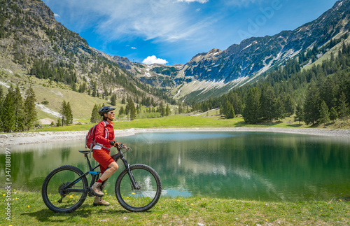 pretty senior woman riding her electric mountain bike at the Seealp lake in the Nebelhorn area above Oberstdorf, Allgau Alps, Bavaria, Germany © Uwe