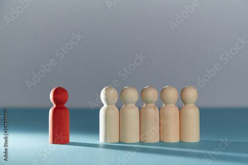 Stay away from people. Social distance. Quarantine period. Stay home be safe. Red wooden figure stand away from crowd