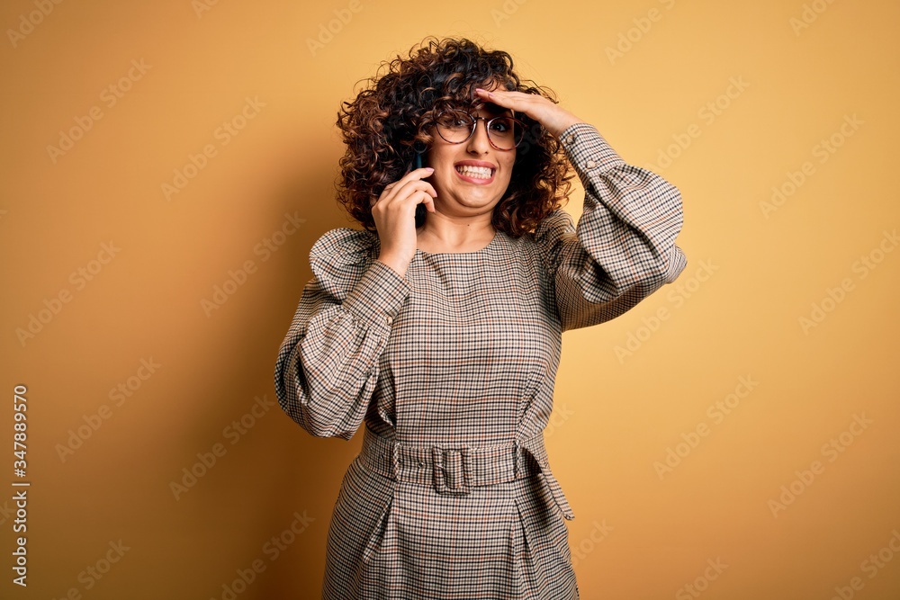 Beautiful arab businesswoman wearing glasses having conversation talking on smartphone stressed with hand on head, shocked with shame and surprise face, angry and frustrated. Fear and upset Beautiful arab businesswoman wearing glasses having conversation talking on smartphone stressed with hand on head, shocked with shame and surprise face, angry and frustrated. Fear and upset