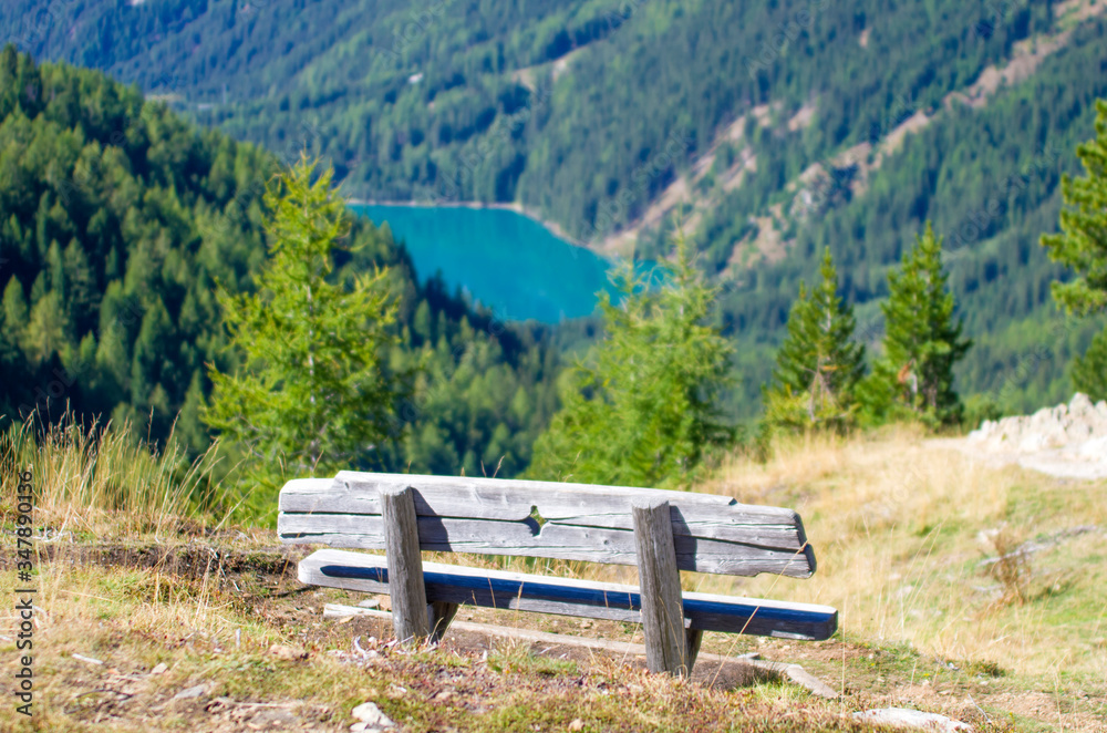 wooden bench to rest hikers and admire the high mountain with lake, meadows, woods and rocks wooden bench to rest hikers and admire the high mountain with lake, meadows, woods and rocks