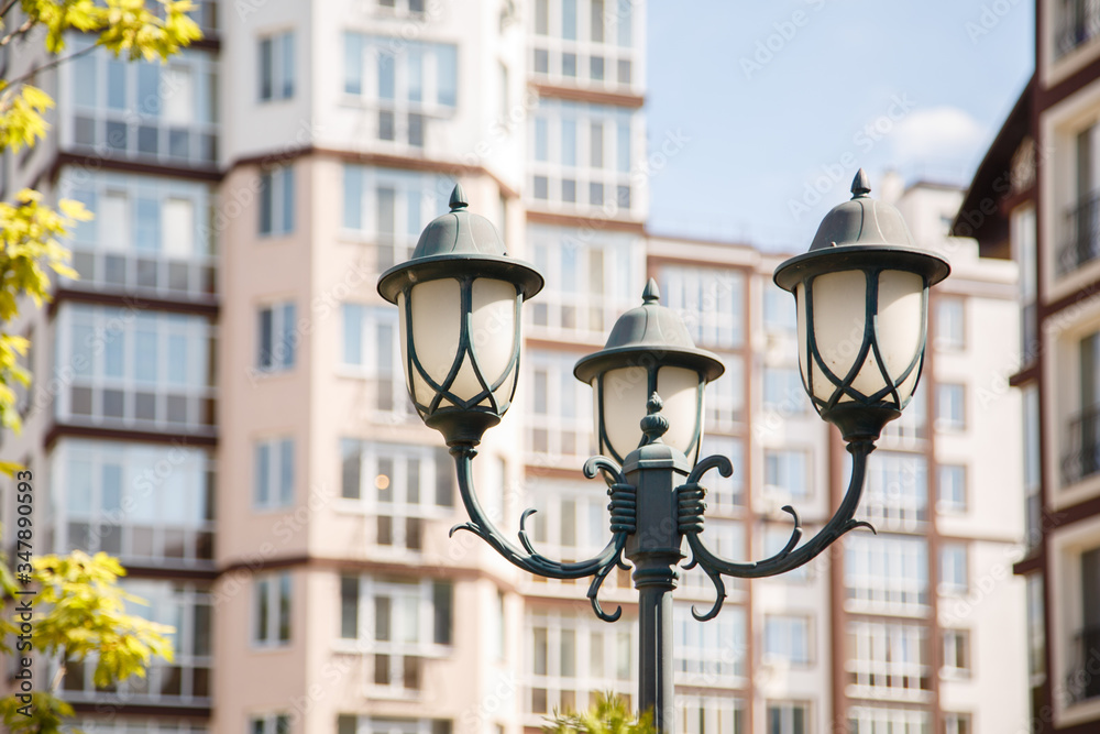 Beautiful lantern on background of new-constructed multi-storey houses. Stylish residential quarter. New family life in the city. Light in the life. Europe building